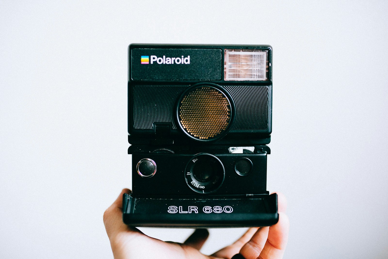 person holding black Polaroid SLR 680 instant camera