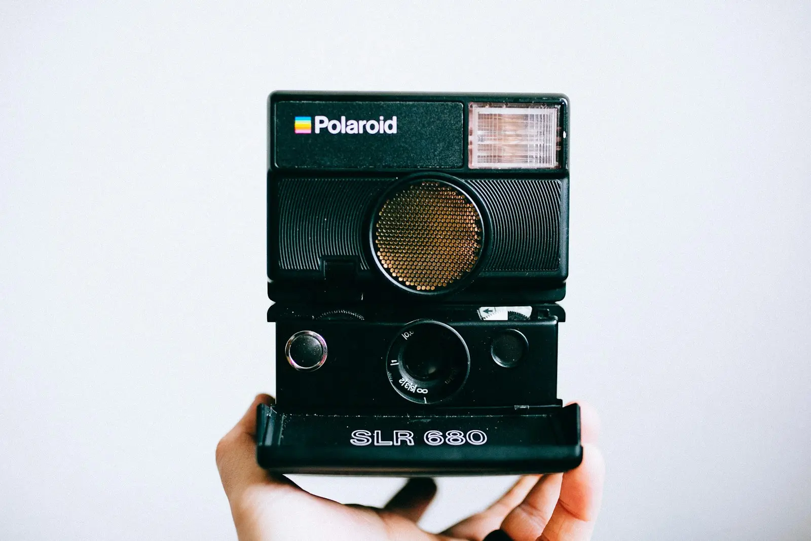 person holding black Polaroid SLR 680 instant camera