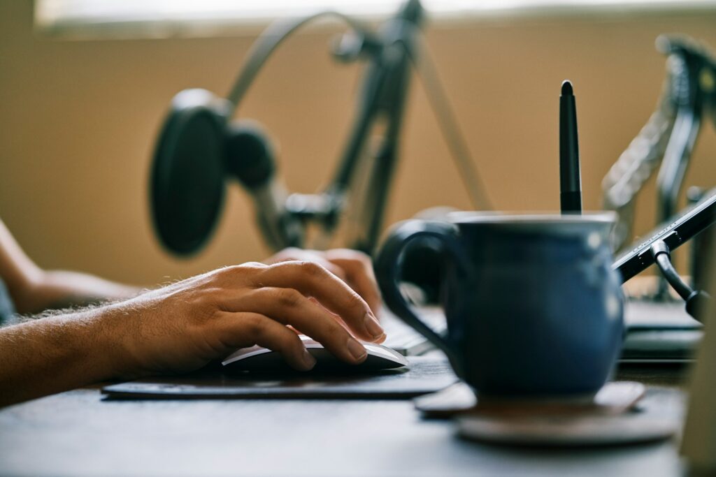 person holding blue ceramic mug on black laptop computer