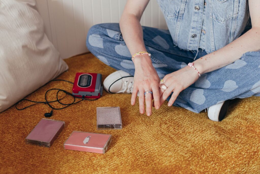 A person in denim with cassette tapes and a Walkman, evoking 90s nostalgia.