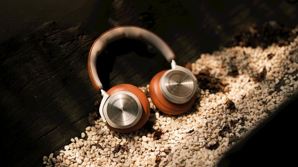 Elegant leather headphones resting on a bed of white pebbles in bright sunlight, exuding luxury and style.