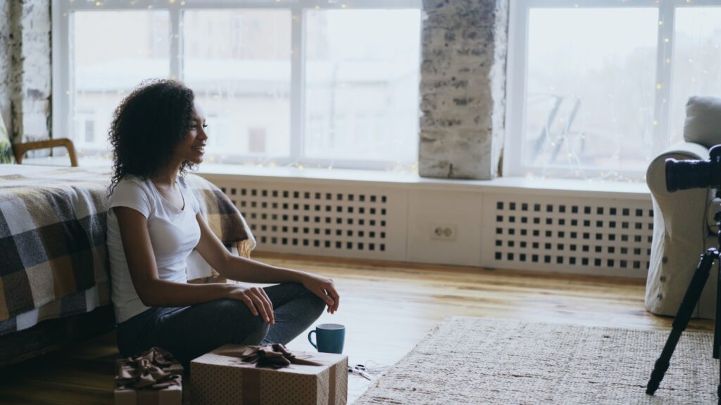 Woman sitting on floor recording video with camera.