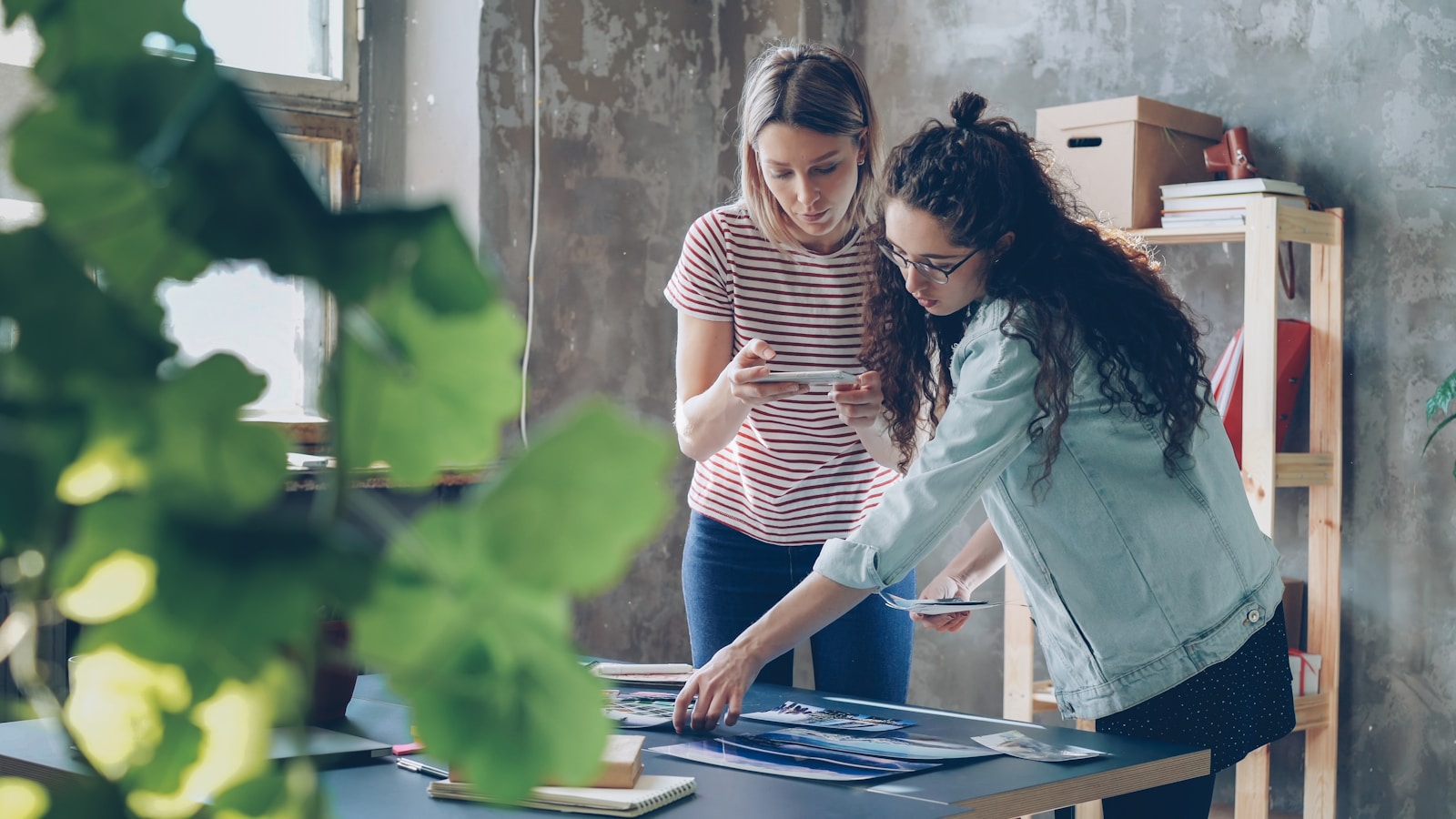 Two women collaborate on work at an office desk