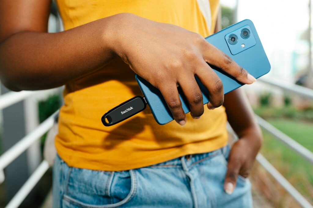 Hand holding smartphone with usb drive plugged in.