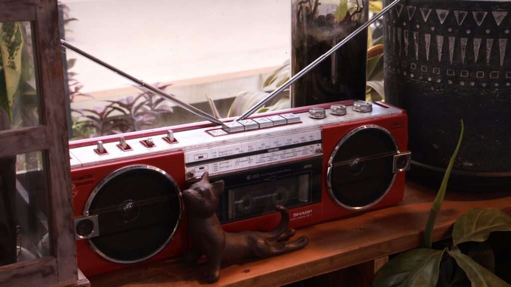 A red vintage boombox on a wooden shelf