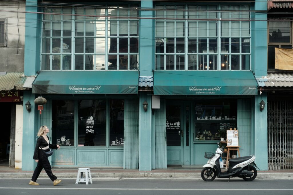 Woman walks past a teal building with a scooter