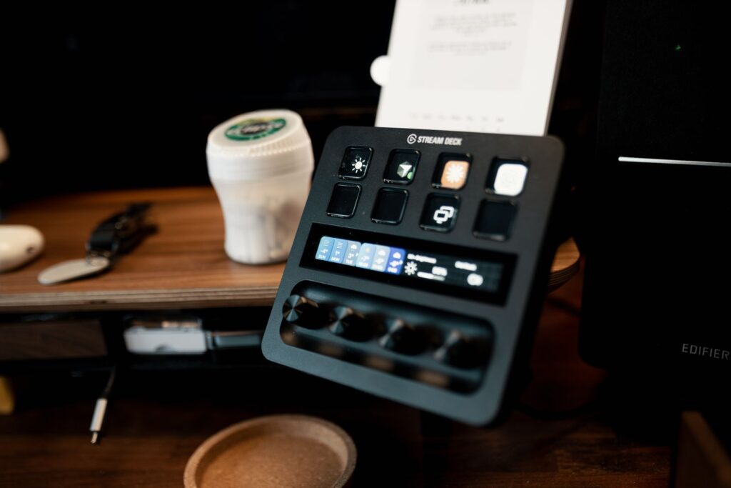A Stream Deck on a wooden desk, featuring various buttons and controls in a home studio setup.